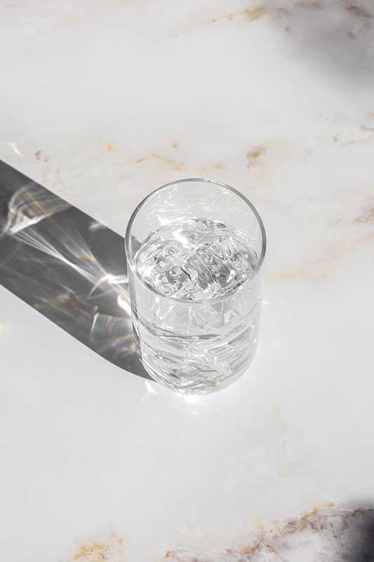 Glass of iced water on marble countertop